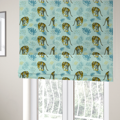 The fabric used to create these Roman blinds is a tropical jungle upholstery fabric on a light mint-blue background featuring a repeating pattern of yellow and black tigers surrounded by teal monstera leaves, palm fronds, and yellow dot clusters.   