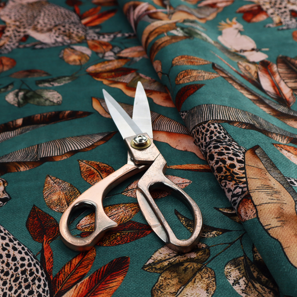A moody teal fabric pattern featuring seated leopards, a toucan, and a white cockatoo amidst autumn-toned tropical leaves and foliage.