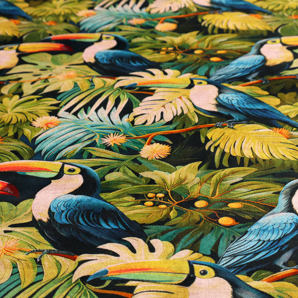 Tropical fabric featuring a repeating pattern of blue toucans perched among lush monstera leaves, palm fronds, and yellow flowers.   