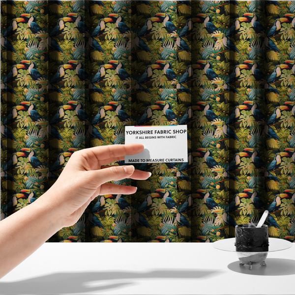 The fabric used to create these made-to-measure curtains is a tropical fabric featuring a repeating pattern of blue toucans perched among lush monstera leaves, palm fronds, and yellow flowers.   