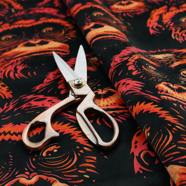 Fabric pattern featuring a repeating graphic illustration of orangutan faces in orange, peach, and reddish-pink tones against a dark black background.   