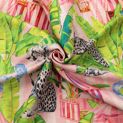 Pink striped fabric with a repeating pattern of seated cheetahs, tropical banana palm leaves, pink striped pavilions, birdcages, and blue porcelain ginger jars.   