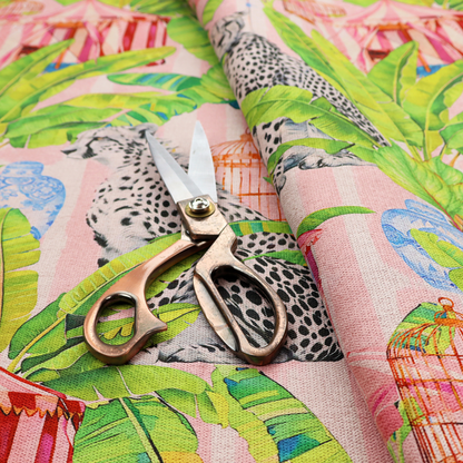 Pink striped fabric with a repeating pattern of seated cheetahs, tropical banana palm leaves, pink striped pavilions, birdcages, and blue porcelain ginger jars.   
