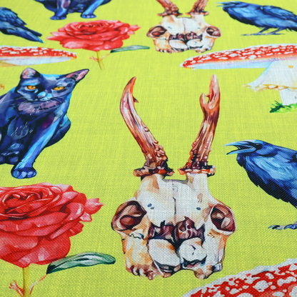 Chartreuse green fabric featuring a repeating pattern of black cats, blue ravens, red roses, horned animal skulls, and red fly agaric mushrooms.   