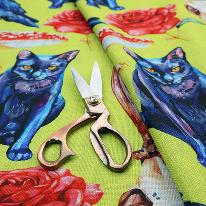 Chartreuse green fabric featuring a repeating pattern of black cats, blue ravens, red roses, horned animal skulls, and red fly agaric mushrooms.   