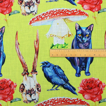Chartreuse green fabric featuring a repeating pattern of black cats, blue ravens, red roses, horned animal skulls, and red fly agaric mushrooms.   