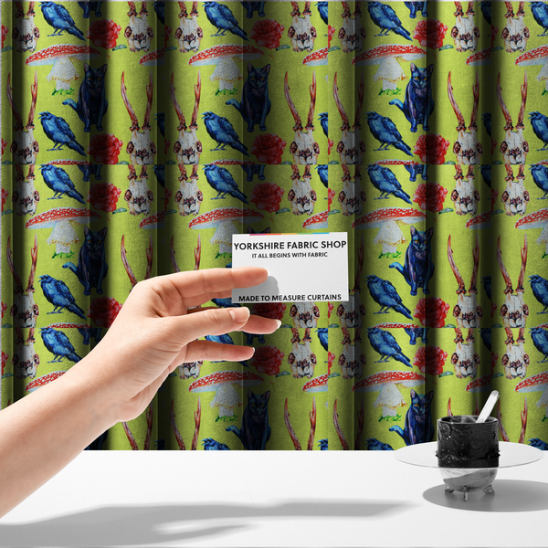 The fabric used to create these made-to-measure curtains is a chartreuse green fabric featuring a repeating pattern of black cats, blue ravens, red roses, horned animal skulls, and red fly agaric mushrooms.   