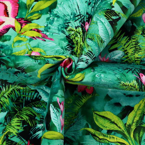 Tropical fabric featuring vibrant magenta parrots in flight surrounded by lush green palm fronds, banana leaves, and pink tropical flowers.   