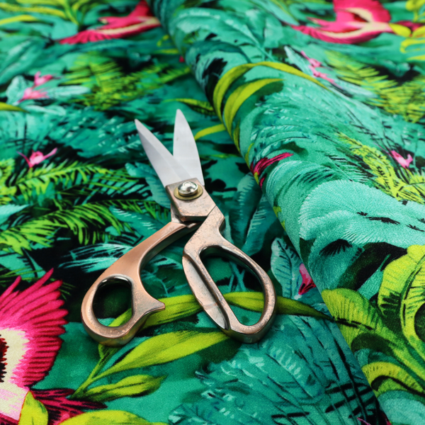 Tropical fabric featuring vibrant magenta parrots in flight surrounded by lush green palm fronds, banana leaves, and pink tropical flowers.   