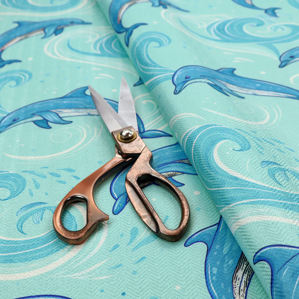 Aqua blue fabric with a repeating pattern of playful blue dolphins leaping through swirling white ocean waves and water splashes.   