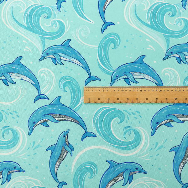 Aqua blue fabric with a repeating pattern of playful blue dolphins leaping through swirling white ocean waves and water splashes.   