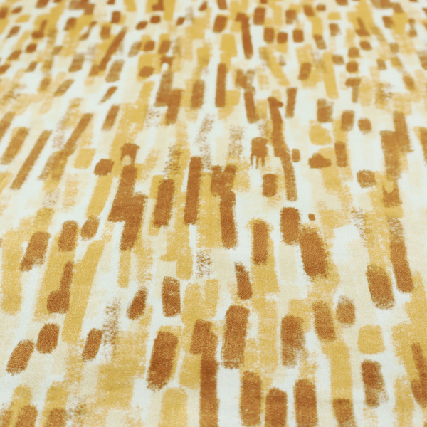 A textured abstract pattern featuring vertical brushstrokes or chalk-like marks in shades of warm mustard yellow and golden brown against a light off-white or cream background.   