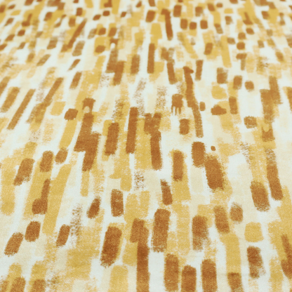 A textured abstract pattern featuring vertical brushstrokes or chalk-like marks in shades of warm mustard yellow and golden brown against a light off-white or cream background.   