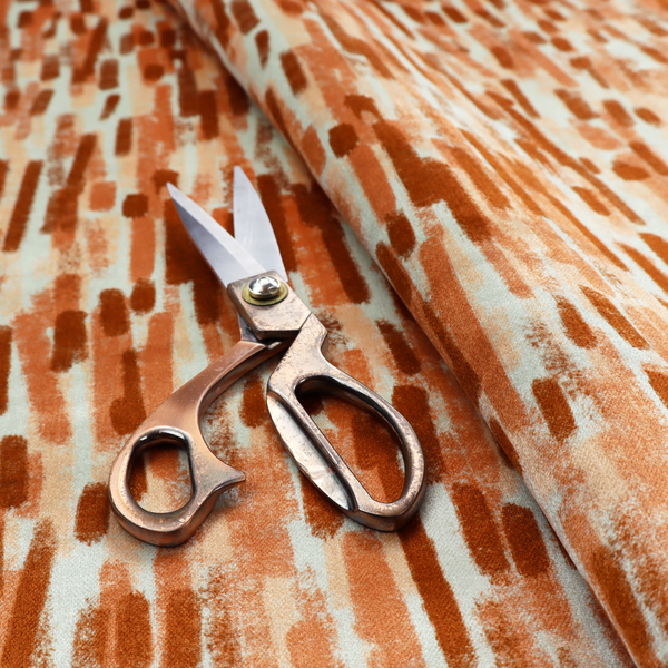 A textured abstract pattern featuring vertical brushstrokes or chalk-like marks in shades of warm terracotta and burnt orange against a light off-white or cream background.