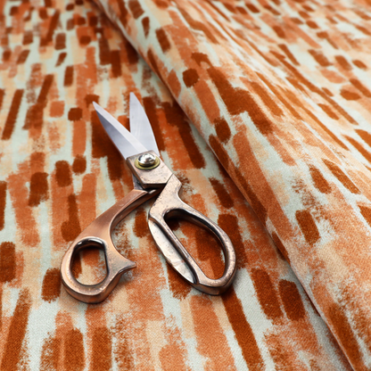 A textured abstract pattern featuring vertical brushstrokes or chalk-like marks in shades of warm terracotta and burnt orange against a light off-white or cream background.