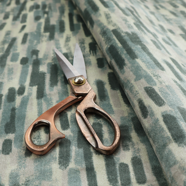Fabric featuring an abstract vertical brushstroke pattern in dark green, sage, and grey on a light neutral background.   