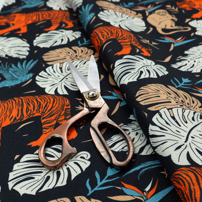 Fabric print featuring orange striped tigers, sitting beige monkeys, flying blue tropical birds, Monstera leaves, and bird of paradise flowers set against a dark navy background.   