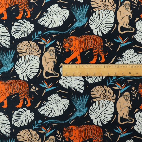 Fabric print featuring orange striped tigers, sitting beige monkeys, flying blue tropical birds, Monstera leaves, and bird of paradise flowers set against a dark navy background.   