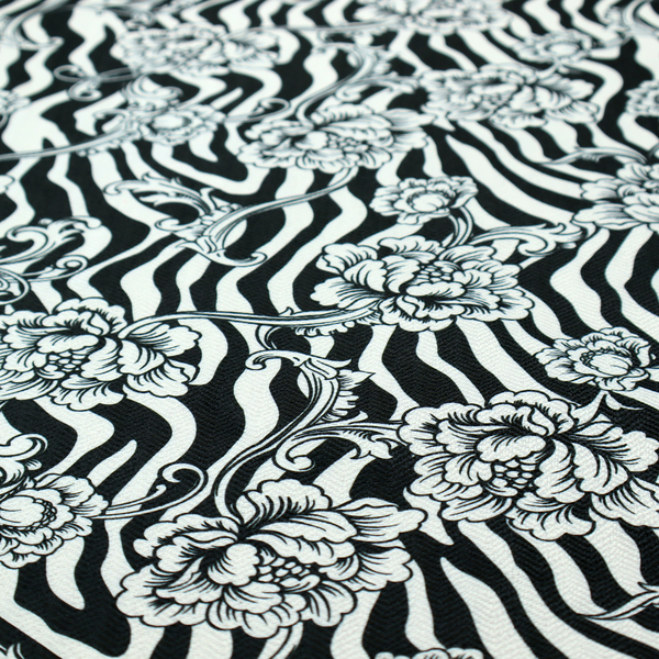 Black and white fabric featuring an ornate floral peony trail layered over a wavy zebra stripe background.   