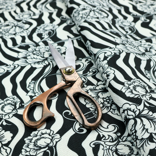 Black and white fabric featuring an ornate floral peony trail layered over a wavy zebra stripe background.   