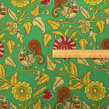 Indian Kalamkari fabric pattern featuring stylized peacocks, golden floral vines, and red rosettes on a vibrant emerald green background.   