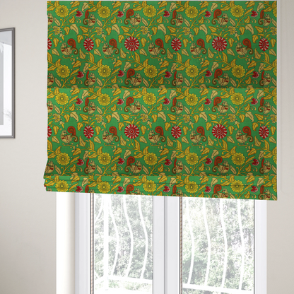 The fabric used to create these Roman blinds is an Indian Kalamkari fabric pattern featuring stylized peacocks, golden floral vines, and red rosettes on a vibrant emerald green background.   
