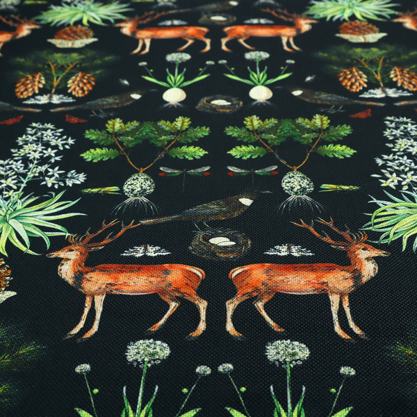 Symmetrical woodland fabric pattern featuring reddish-brown stags with antlers, pinecones, birds, nests with eggs, and botanical flora on a black background.   
