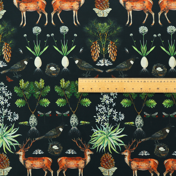 Symmetrical woodland fabric pattern featuring reddish-brown stags with antlers, pinecones, birds, nests with eggs, and botanical flora on a black background.   