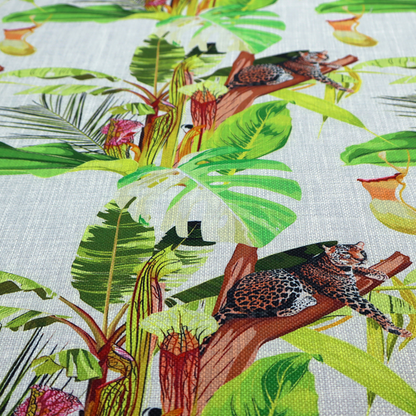 Tropical jungle fabric featuring leopards resting on tree branches alongside pitcher plants, banana leaves, and Monstera foliage on a light grey textured background.