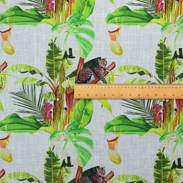 Tropical jungle fabric featuring leopards resting on tree branches alongside pitcher plants, banana leaves, and Monstera foliage on a light grey textured background.