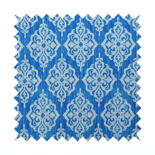 Vibrant royal blue woven fabric featuring an ornate, repeating white damask medallion pattern with a textured ikat effect.   