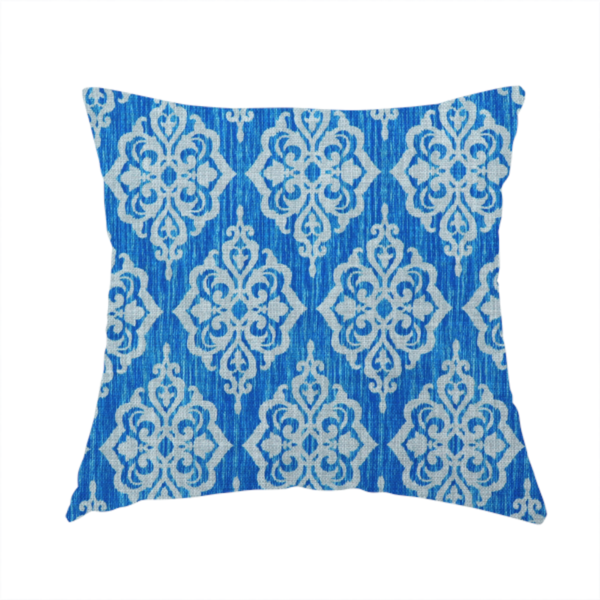 The fabric used to create this handmade cushion is a vibrant royal blue woven fabric featuring an ornate, repeating white damask medallion pattern with a textured ikat effect.   