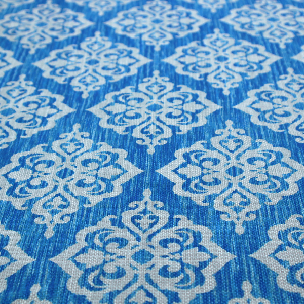 Vibrant royal blue woven fabric featuring an ornate, repeating white damask medallion pattern with a textured ikat effect.   