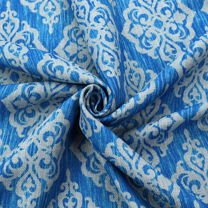 Vibrant royal blue woven fabric featuring an ornate, repeating white damask medallion pattern with a textured ikat effect.   