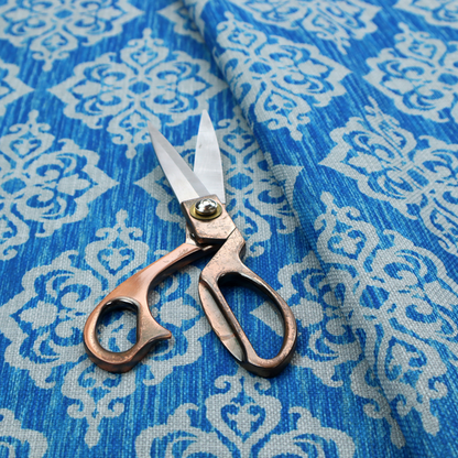 Vibrant royal blue woven fabric featuring an ornate, repeating white damask medallion pattern with a textured ikat effect.   