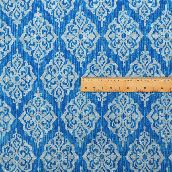 Vibrant royal blue woven fabric featuring an ornate, repeating white damask medallion pattern with a textured ikat effect.   