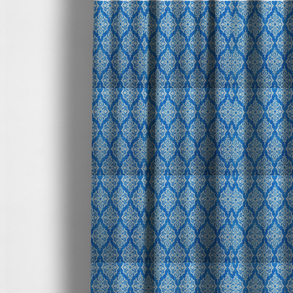 The fabric used to create these made-to-measure curtains is a vibrant royal blue woven fabric featuring an ornate, repeating white damask medallion pattern with a textured ikat effect.   