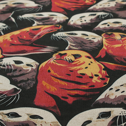 Fabric print featuring a repeating pattern of seals and sea lions in shades of cream, ochre yellow, and coral red on a dark charcoal background.   
