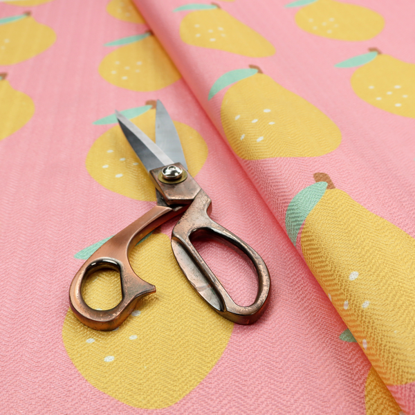 Pink fabric with a repeating pattern of yellow lemons, light green leaves, and small white dots.