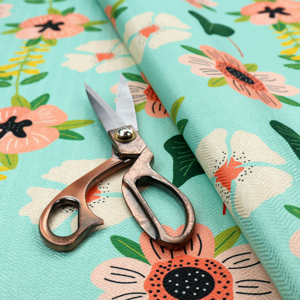 Whimsical floral fabric featuring peach and cream flowers, yellow vining stems, and dark green heart-shaped leaves on a light mint turquoise background.   