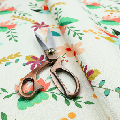 Playful floral fabric featuring scattered colourful bouquets with light blue, coral, purple, and peach blossoms among green stems and mustard foliage on a off-white background.   