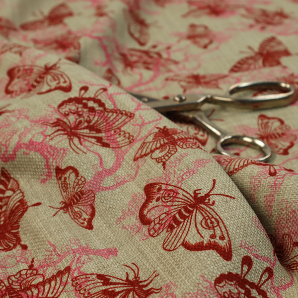 This fabric layers large red butterflies on top of pink tree illustrations, on a neutral background.