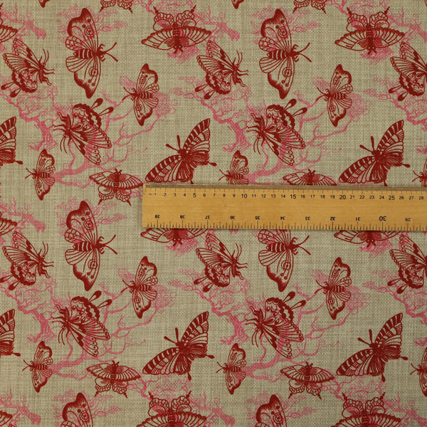 This fabric layers large red butterflies on top of pink tree illustrations, on a neutral background.