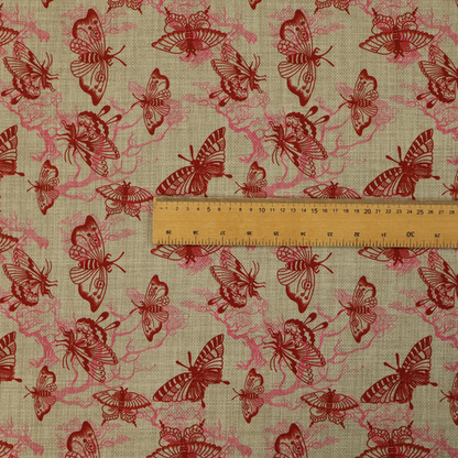 This fabric layers large red butterflies on top of pink tree illustrations, on a neutral background.