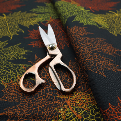 An autumn botanical fabric pattern featuring detailed skeleton maple leaf outlines in rust red, olive green, and gold on a black background.