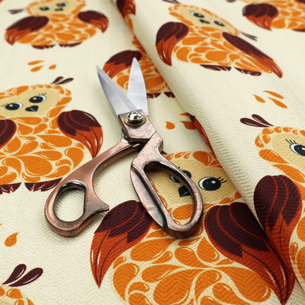 A repeating fabric pattern featuring illustrated owls with paisley-patterned bodies in warm orange, brown, and ochre on a cream background.