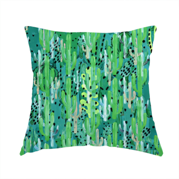 The fabric used to create this handmade cushion is a vibrant, dense pattern of stylized painted saguaro cacti and succulents in shades of green, mint, and white with black polka dots and dashes over a turquoise background.