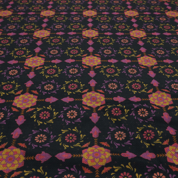 An intricate geometric fabric pattern featuring repeating mandala motifs, floral medallions, and ornate tiles in shades of pink, orange, yellow, and purple set against a dark black background.
