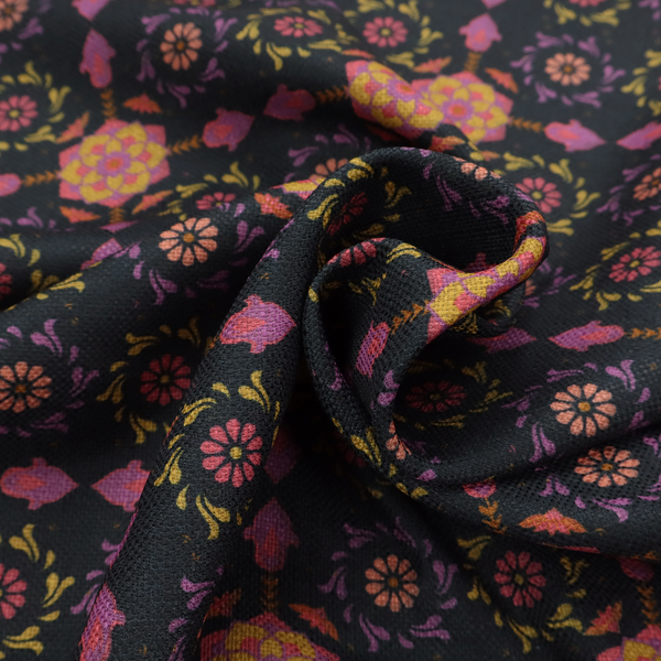 An intricate geometric fabric pattern featuring repeating mandala motifs, floral medallions, and ornate tiles in shades of pink, orange, yellow, and purple set against a dark black background.