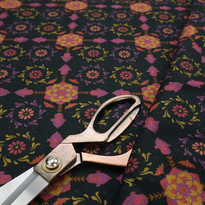 An intricate geometric fabric pattern featuring repeating mandala motifs, floral medallions, and ornate tiles in shades of pink, orange, yellow, and purple set against a dark black background.